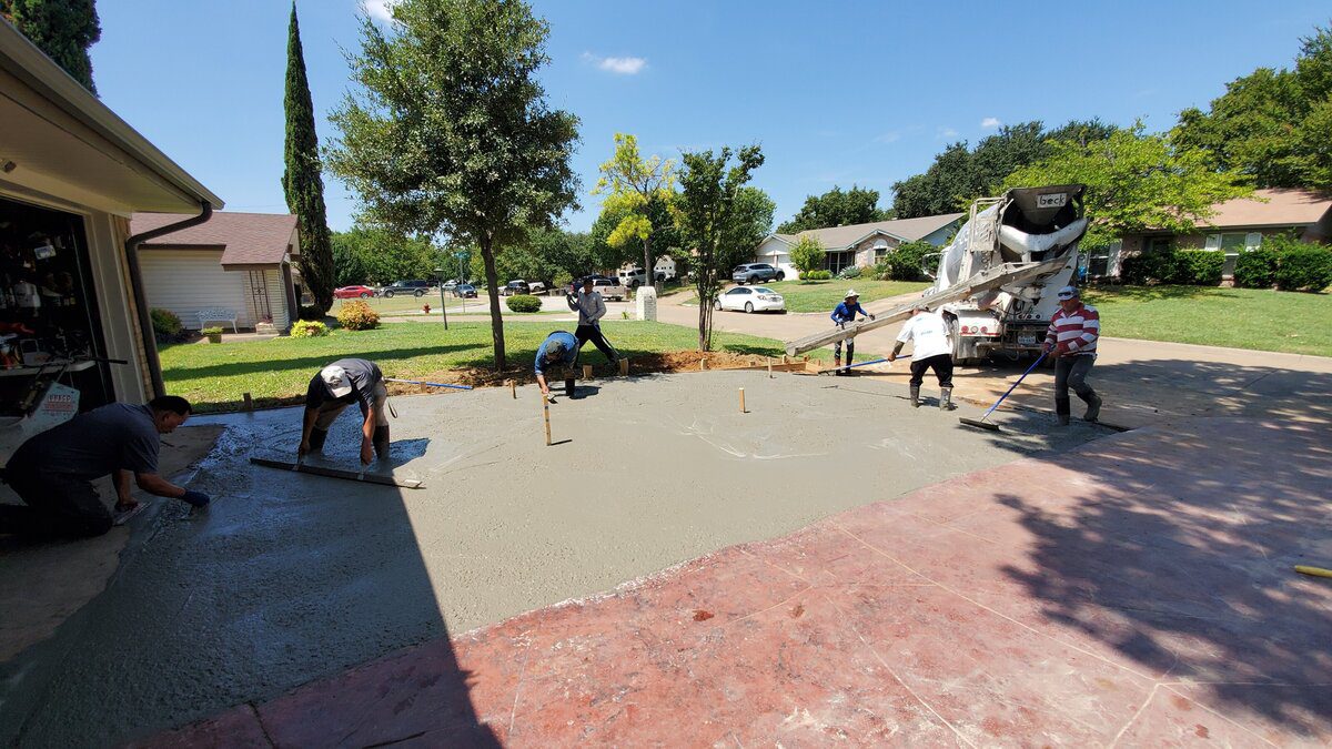 Workers smoothing freshly poured concrete driveway.
