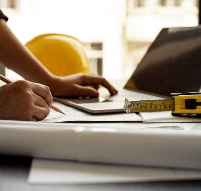 Person working with laptop and construction plans.