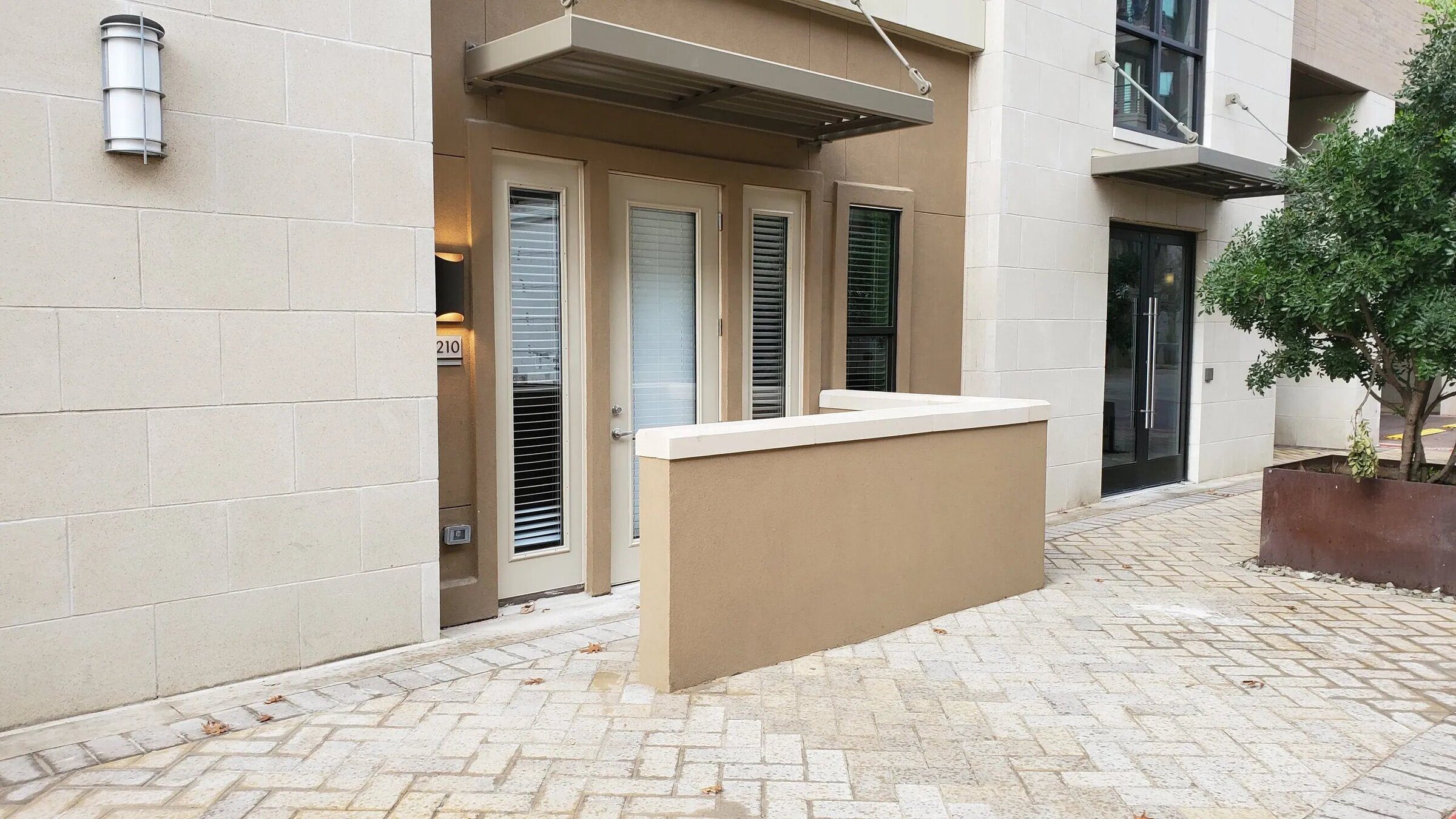 Apartment entrance with glass door and plants.