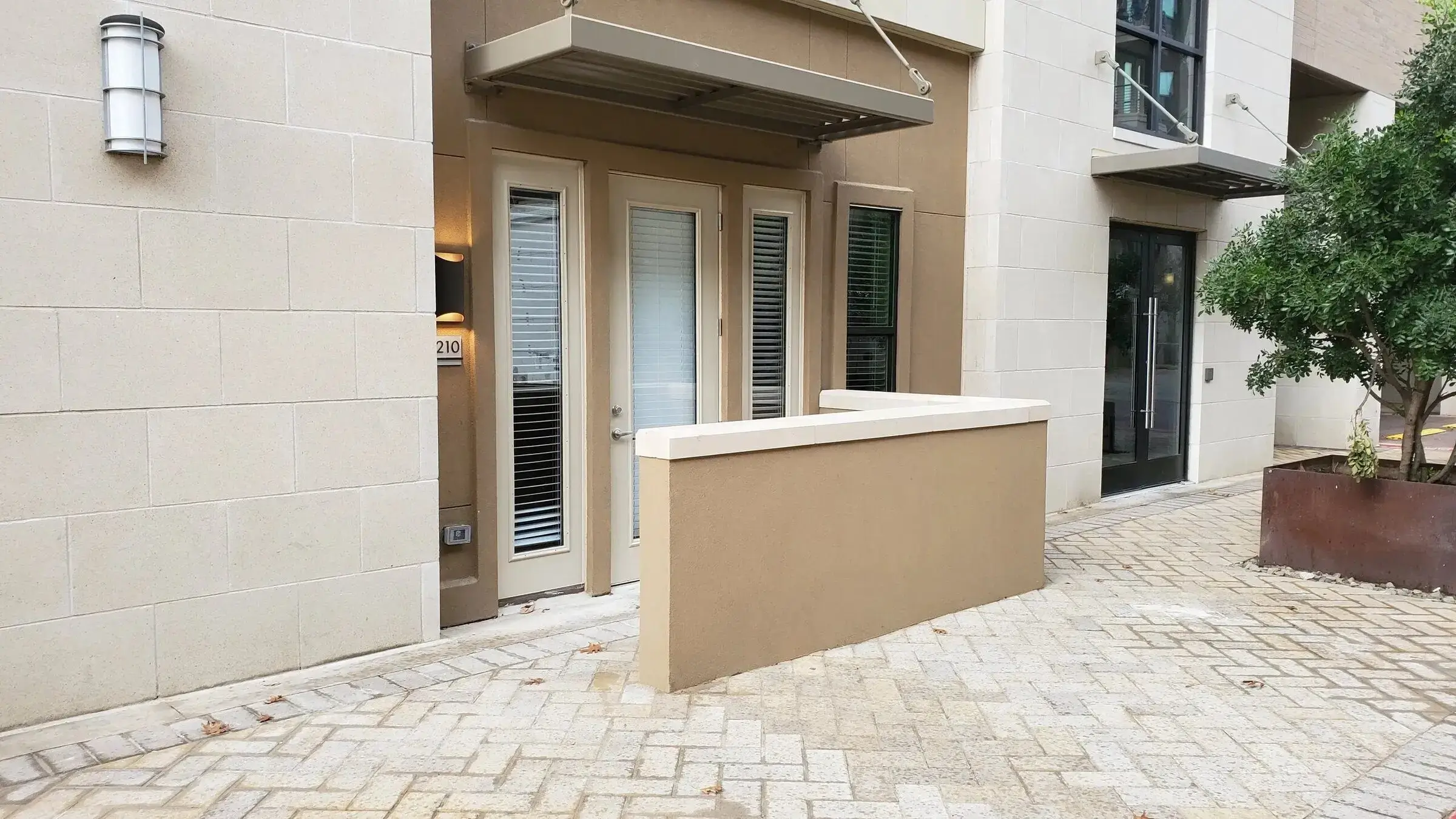 Apartment entrance with glass door and plants.